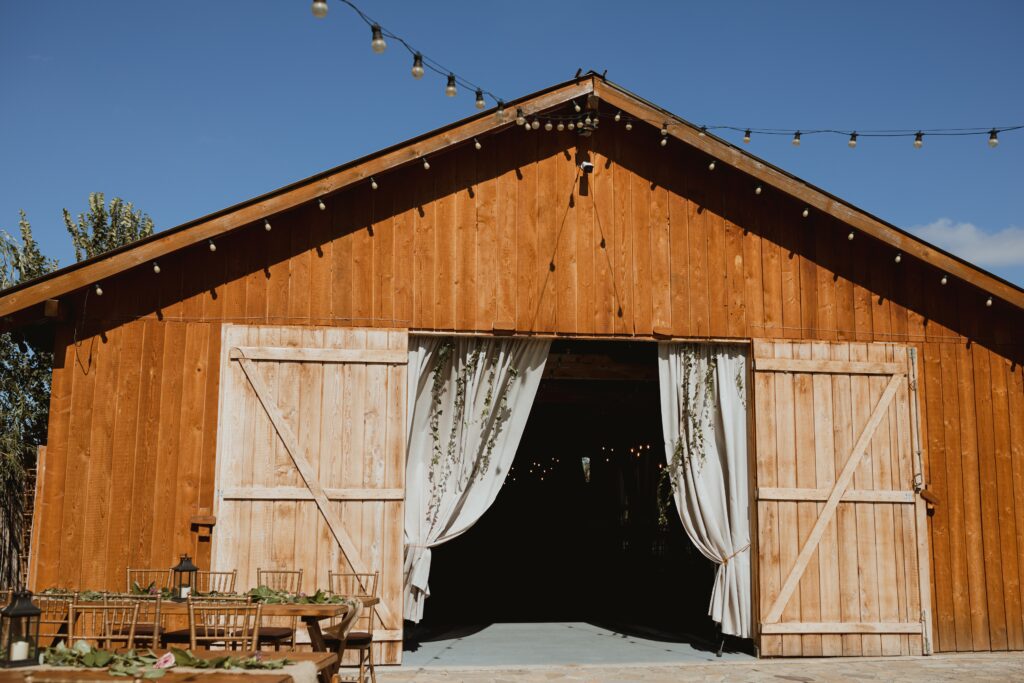 A brown barn building with doors open and drapes inside.