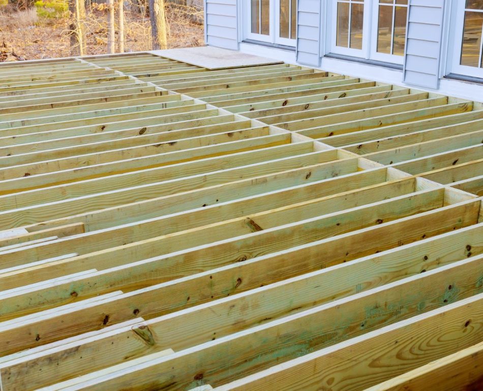 A wooden deck attached to a white home in the process of being installed.